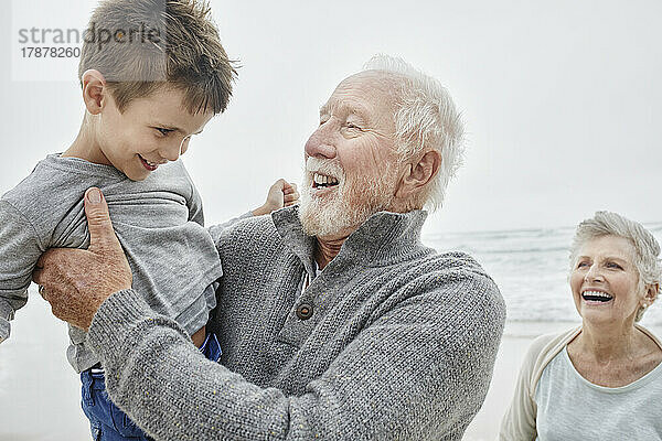 Glückliche Großeltern verbringen schöne Zeit mit ihrem Enkel am Strand