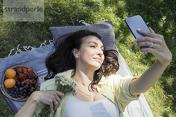 Lächelnde Frau  die im Park ein Selfie mit dem Mobiltelefon macht