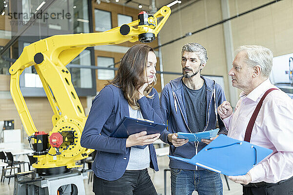 Ingenieure in der Fabrik treffen sich vor einem Industrieroboter