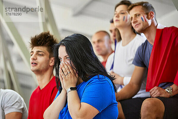 Frau mit Händen vor Mund drückt Enttäuschung über Sportveranstaltung im Stadion aus