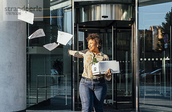 Glückliche Geschäftsfrau wirft Papiere vor der Tür weg