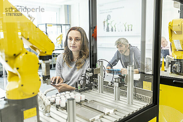 Frau arbeitet in einer Roboterfabrik mit digitalem Tablet