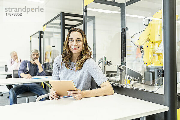 Frau arbeitet in einer Roboterfabrik mit digitalem Tablet