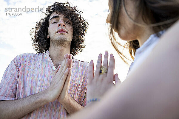 Young couple meditating with hands clasped