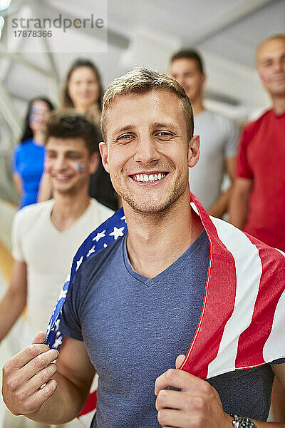 Lächelnder Mann mit amerikanischer Flagge bei Sportveranstaltung im Stadion