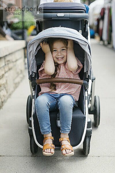 Lächelndes Mädchen (2-3) im Kinderwagen