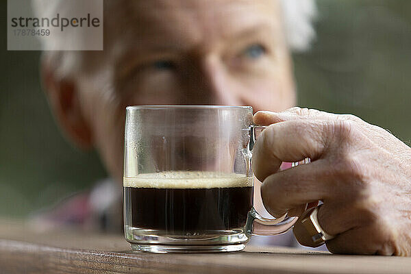 Älterer Mann greift nach einer Kaffeetasse