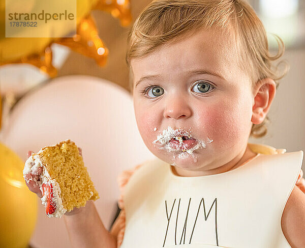 Kleines Mädchen (12–17 Monate) isst Geburtstagstorte