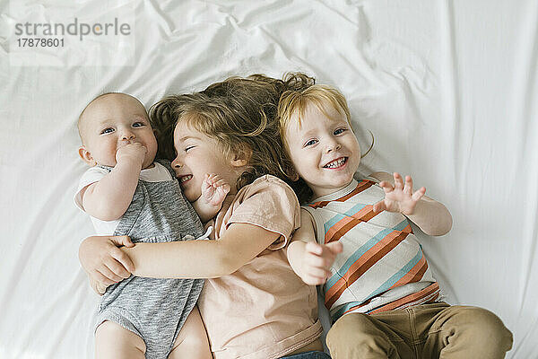 Geschwister (6-11 Monate  2-3) umarmen sich im Bett