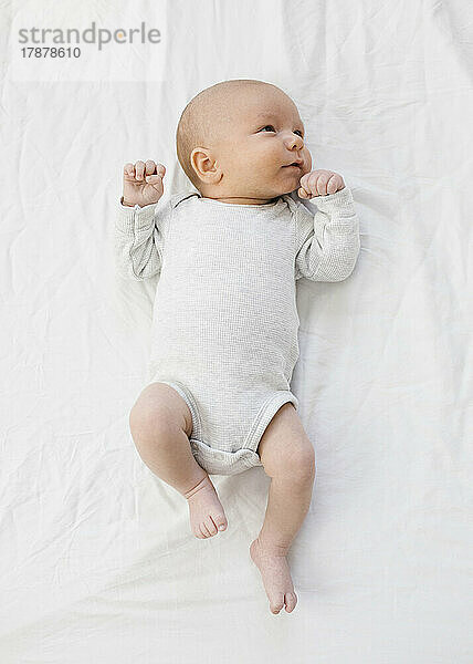 Draufsicht auf einen neugeborenen Jungen (0–1 Monat)  der auf dem Bett liegt