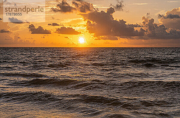 Goldene Wolken über dem Meer bei Sonnenaufgang