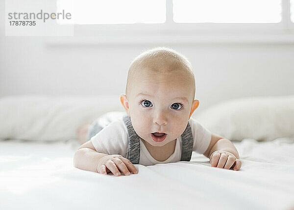 Porträt eines kleinen Jungen (6-11 Monate)  der auf dem Bett liegt