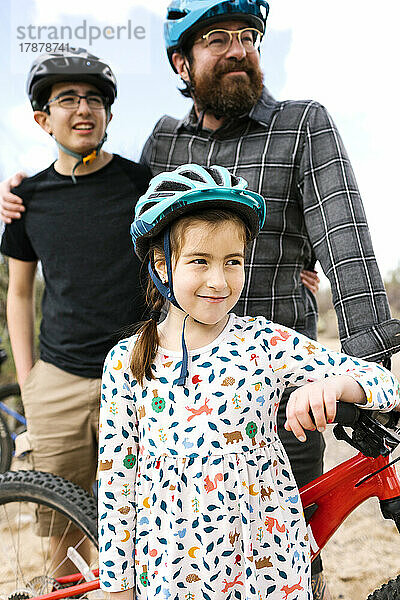 Vater mit Kindern (8–9  14–15)  die Fahrradhelme tragen