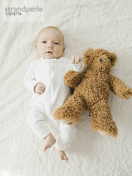 Baby Junge (2-5 Monate) Junge liegt mit Teddybär im Bett