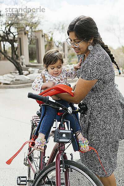 Mutter setzt Tochter (2-3) in Fahrradsitz