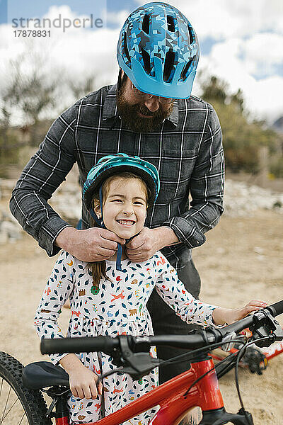 Vater passt Fahrradhelm seiner Töchter (8-9) an