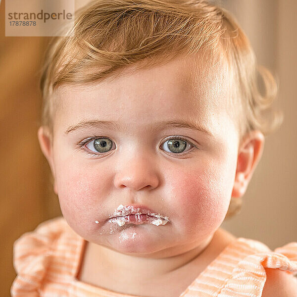 Porträt eines kleinen Mädchens (12–17 Monate) mit Zuckerguss um den Mund