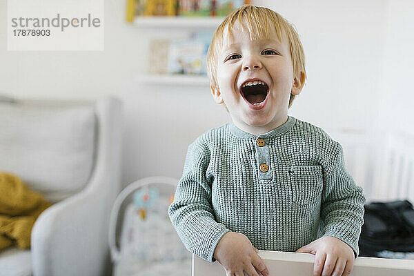 Lächelnder kleiner Junge (2-3) im Kinderbett