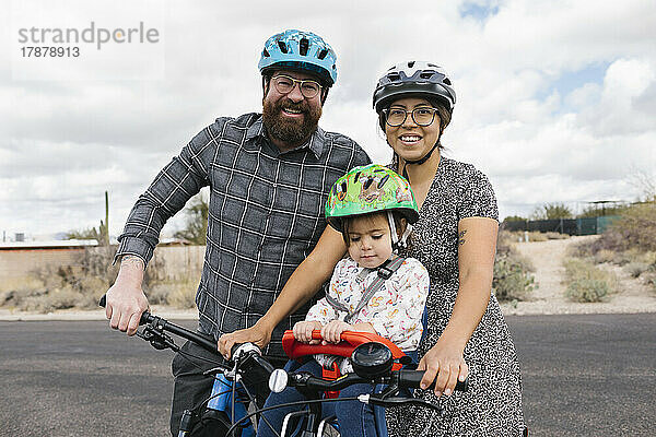 Porträt einer Familie mit Tochter (2-3) beim gemeinsamen Radfahren