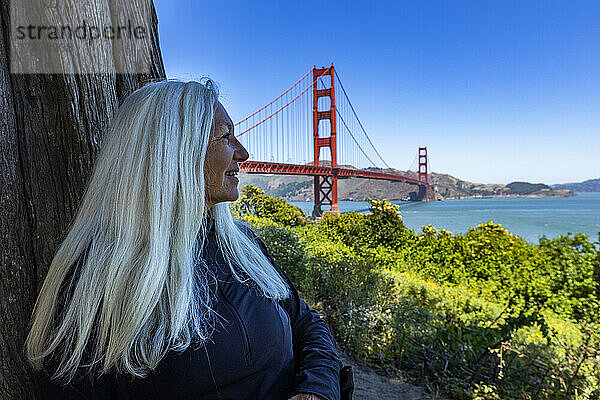 USA  Kalifornien  San Francisco  Seniorin sitzt im Schatten mit Blick auf die Golden Gate Bridge