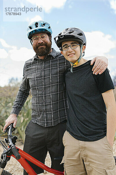 Porträt von Vater und Sohn (14-15) mit Fahrradhelmen