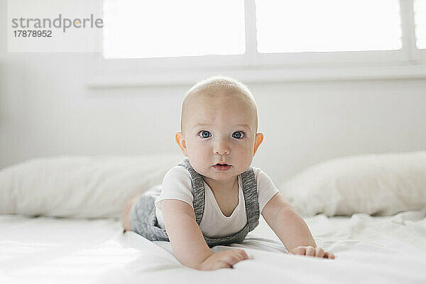 Porträt eines kleinen Jungen (6-11 Monate) auf dem Bett