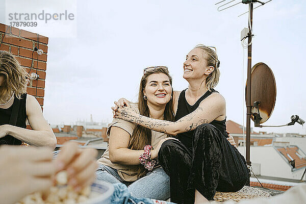 Glückliche Frau sitzt mit einer Freundin auf dem Dach