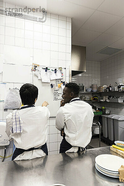 Männliche und weibliche Kollegen planen am Whiteboard in der Restaurantküche