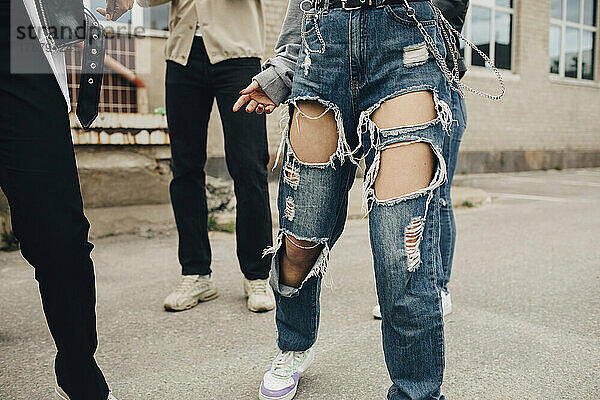 Tiefschnitt einer Frau in zerrissenen Jeans  die mit Freunden auf der Straße tanzt