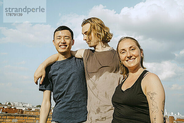 Porträt von glücklichen multirassischen Freunden  die an einem sonnigen Tag vor dem Himmel stehen
