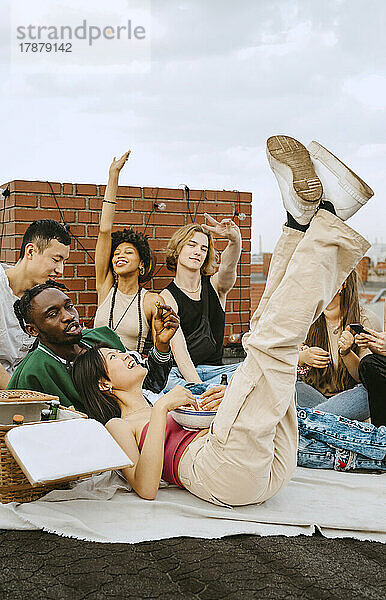 Glückliche männliche und weibliche Freunde genießen zusammen auf dem Dach