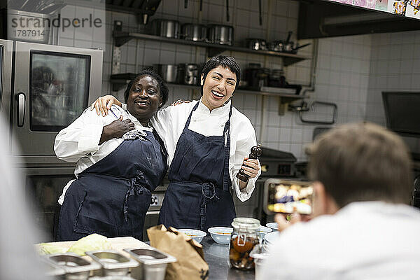 Männlicher Chefkoch fotografiert glückliche Kollegen in einer Großküche