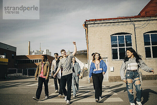 Glückliche multirassische junge Freunde beim Überqueren der Straße in der Stadt