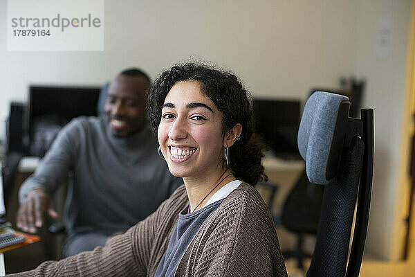 Porträt einer glücklichen Geschäftsfrau  die mit einem Kollegen im Büro sitzt