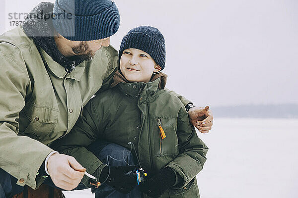 Lächelnder Junge in warmer Kleidung sieht seinen Vater im Winter an