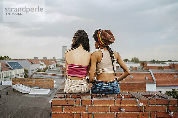 Rückansicht von jungen Frauen  die auf einem Dach zusammensitzen