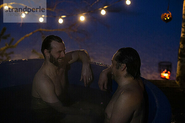 Glückliche  hemdsärmelige  reife Männer unterhalten sich beim Baden im Whirlpool