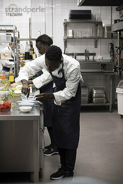 Männliche und weibliche Köche arbeiten an der Küchentheke eines Restaurants