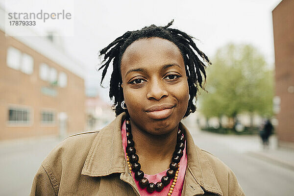 Portrait lächelnde junge Frau mit geflochtenem Haar auf der Straße