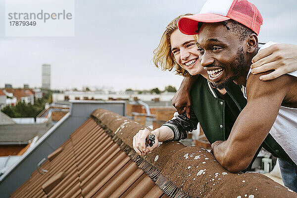 Männliche Freunde lachen auf dem Dach und genießen