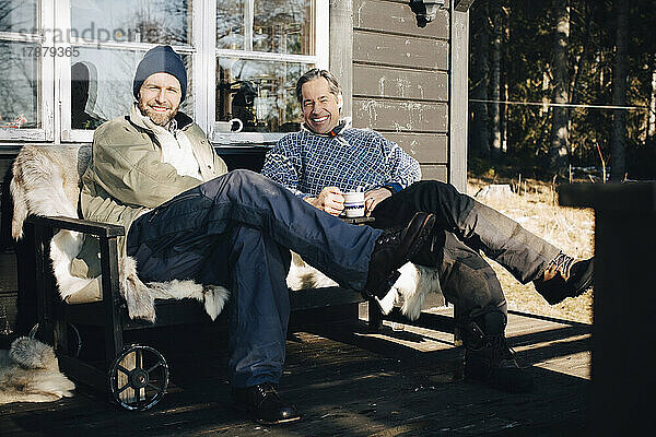 Porträt in voller Länge von glücklichen reifen Männern  die zusammen auf der Veranda sitzen
