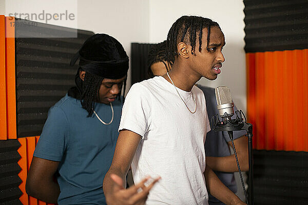 Teenager-Rapper mit Freunden  die im Studio einen Song am Mikrofon aufnehmen