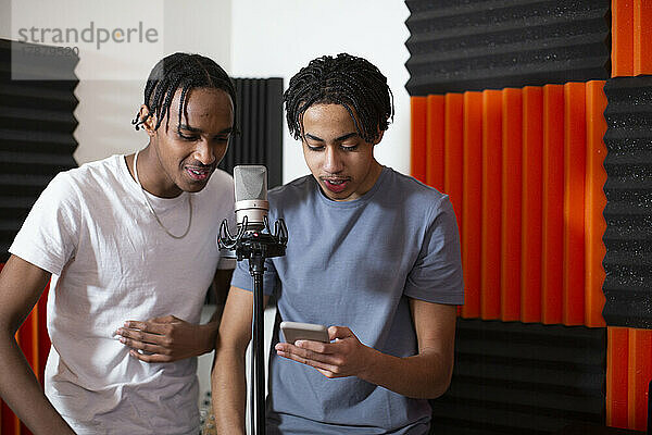 Teenager-Rapper teilen sich ein Smartphone  während sie einen Song im Studio aufnehmen