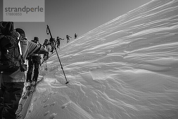 Gruppe auf Skiern  die hintereinander einen verschneiten Berg erklimmt