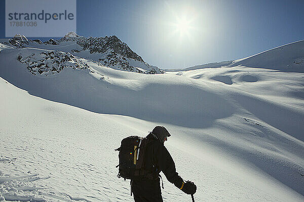 Männlicher Skifahrer mit Rucksack am sonnigen  verschneiten Berghang  Selkirk Mountains  Kanada