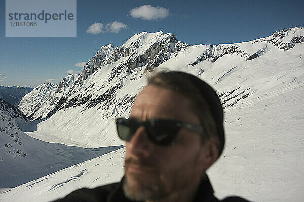 Mann mit Sonnenbrille auf sonnigem  verschneitem Berg  Selkirk Mountains  Kanada