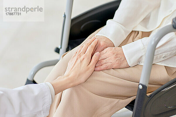 Japanische Seniorin im Rollstuhl und Krankenschwester