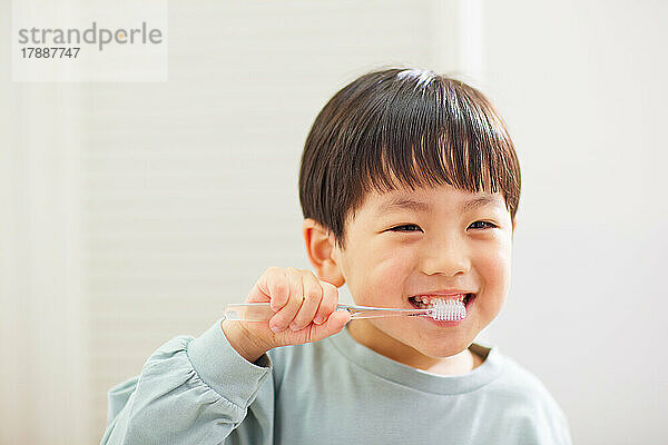 Japanisches Kind putzt zu Hause Zähne