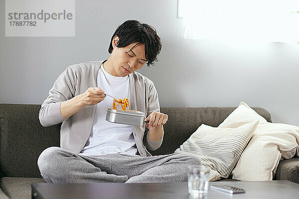Japaner  der auf dem Sofa isst