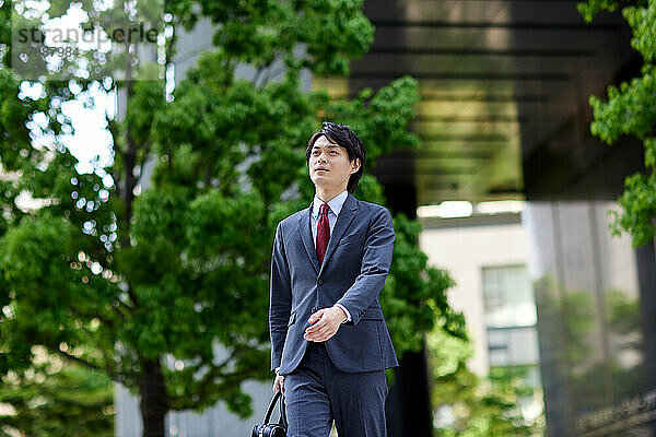 Japanischer Geschäftsmann geht im Geschäftsviertel spazieren